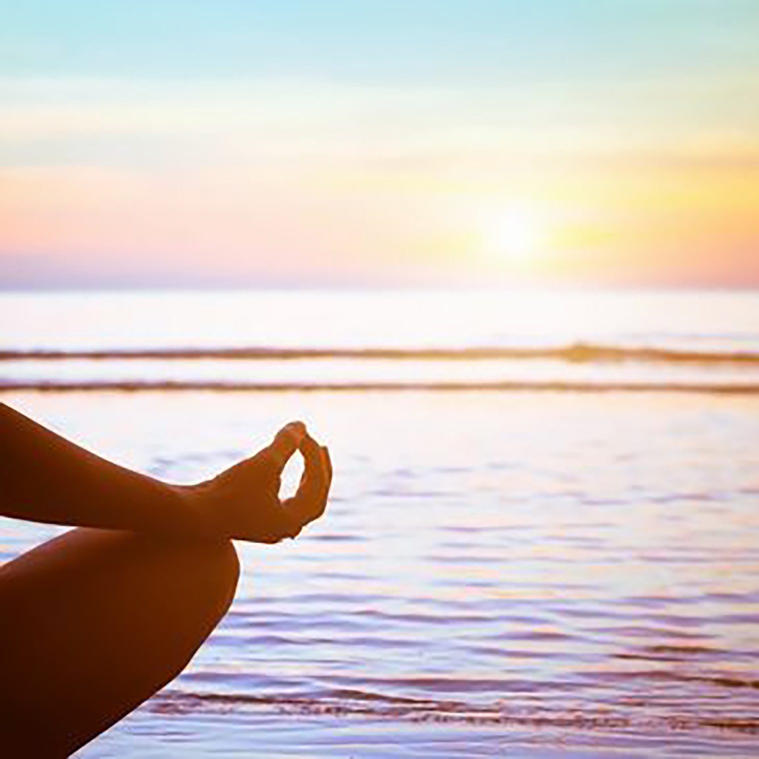 A person sitting in the lotus position on the beach