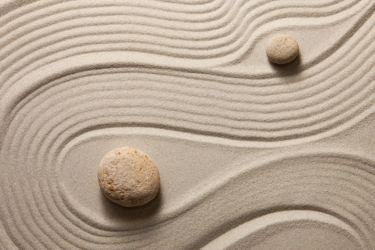 Two stones are sitting on a sand pattern.